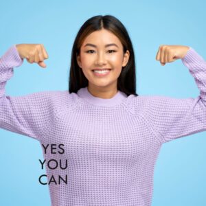 A motivated woman in a purple sweater flexing her arms with the words "YES YOU CAN" displayed, symbolizing the achievement of short-term goals.