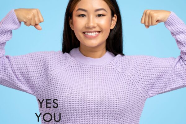 A motivated woman in a purple sweater flexing her arms with the words "YES YOU CAN" displayed, symbolizing the achievement of short-term goals.